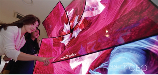 65인치 초고화질(UHD) 유기발광다이오드(OLED) 디스플레이 4장을 둥글게 구부려 장미꽃 모양으로 붙인 조형물을 소개하고 있는 모델들