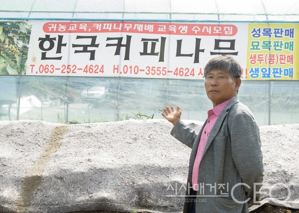 ㈜한국커피나무 오흥석 대표가 상호앞에 선 상태로 사진촬영에 집중하고 있다. 사진촬영=시사매거진CEO 이 신 기자